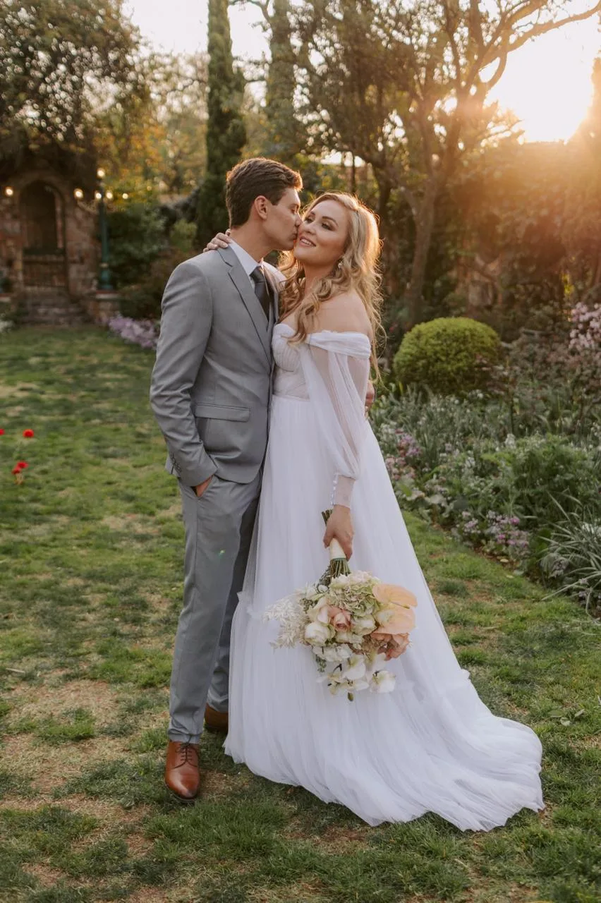 Couple embracing in a garden at sunset, peach and cream bouquet by Equilibrium Flower Studio