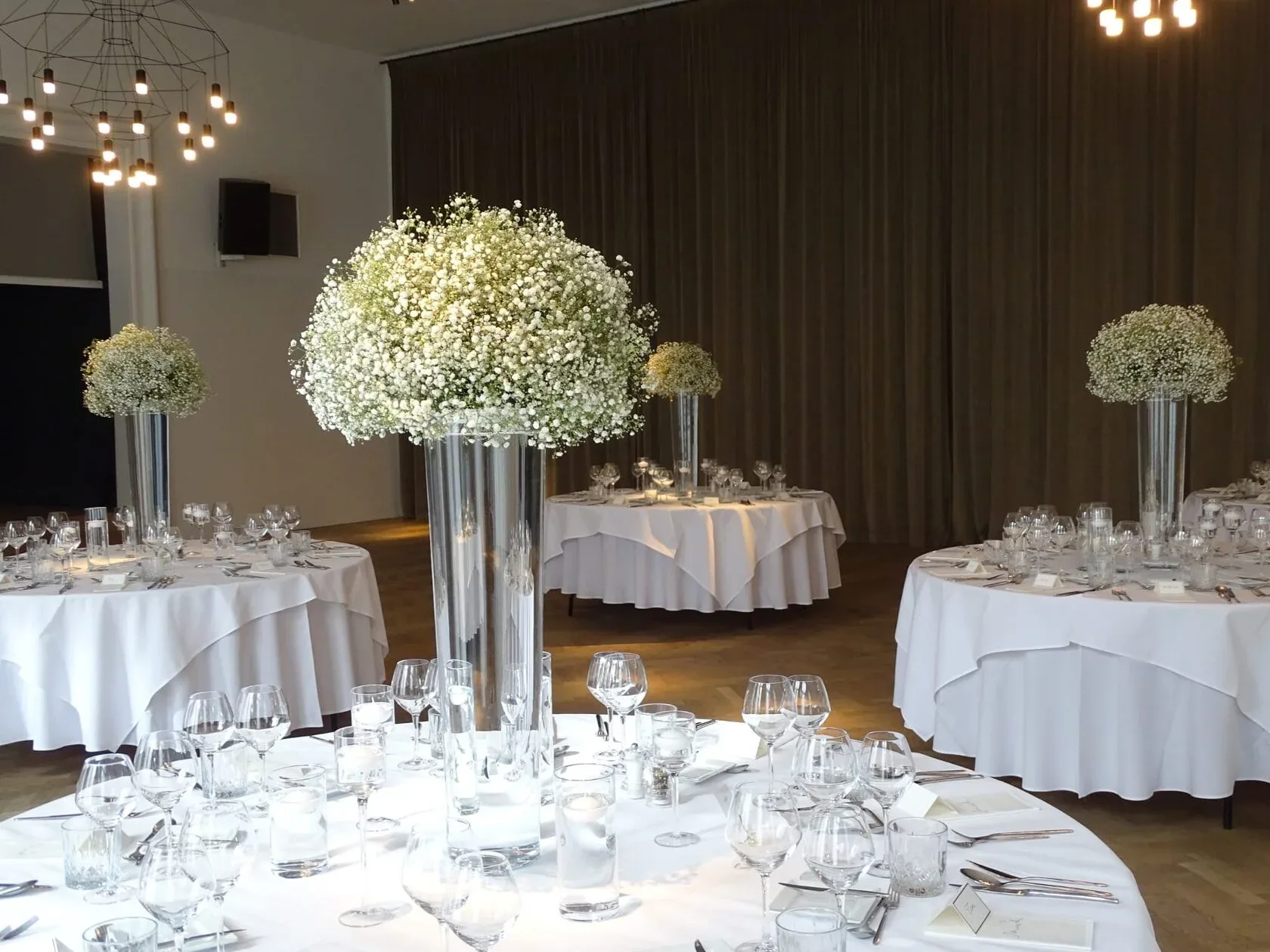Round reception tables with tall gypsophila arrangements in glass vases, by Equilibrium Flower Studio